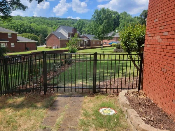 161 feet of 4 foot flat top black aluminum fence beside a brick home