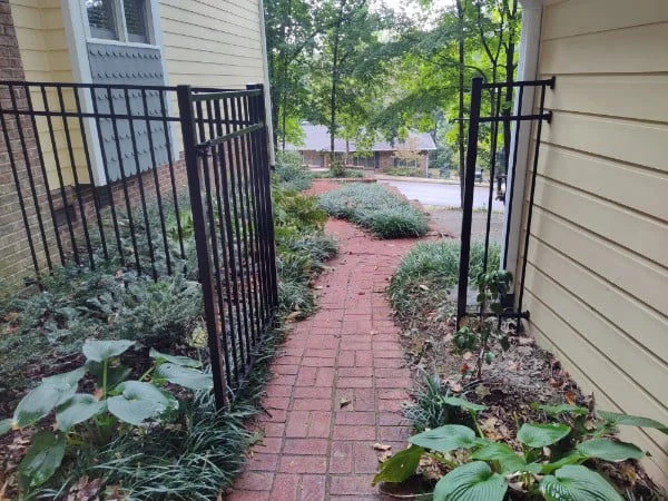 Black aluminum fence beside a brick garden path