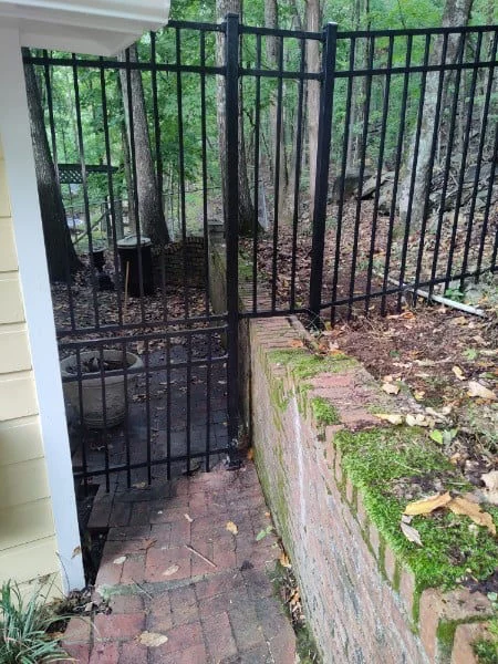 Black ornamental metal gate between masonry posts