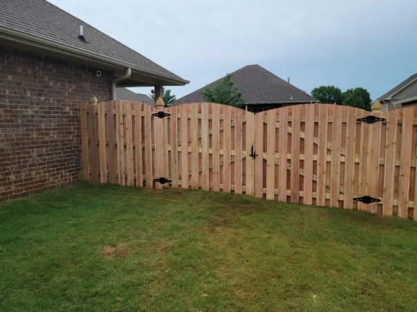 Arched top section of a 6 foot board to board wood fence between capped posts