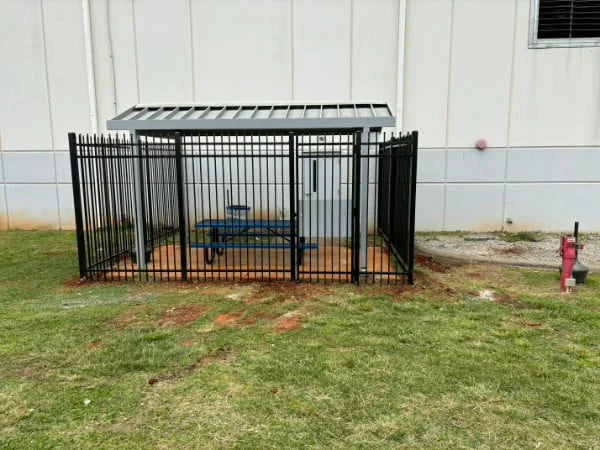 Black chain link enclosure protecting mechanical equipment at a business