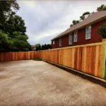 Stained cedar privacy fence curving along a residential driveway