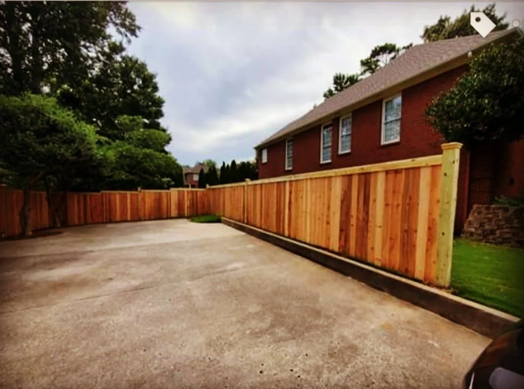 Stained cedar privacy fence curving along a residential driveway