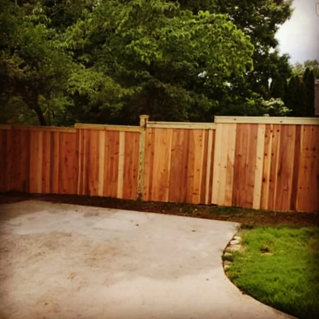Stained wood privacy fence along a mown lawn
