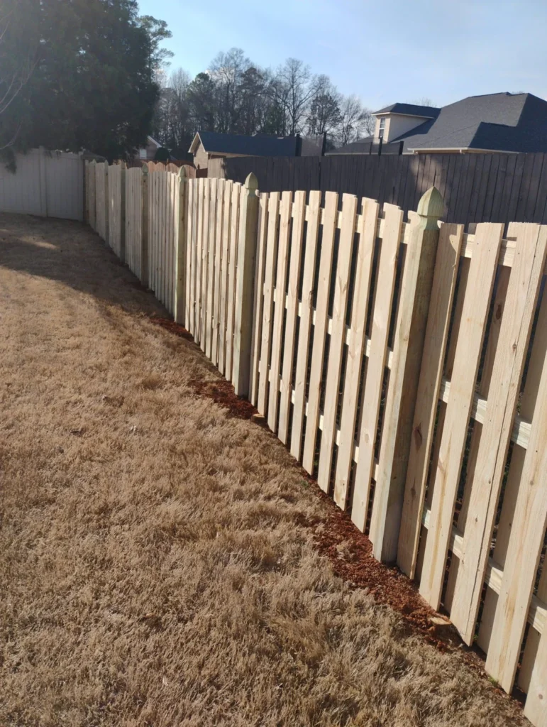 Wood picket fence running along the edge of a yard